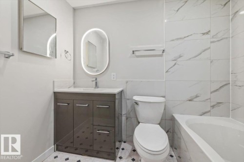 This bathroom features a contemporary vanity with a white countertop and an illuminated oval mirror - 12C Castle Terrace, Edmonton, AB - Indoor Photo Showing Bathroom