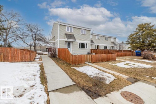 The property features a light-colored siding exterior, private fencing, and a paved walkway leading to the entrance - 12C Castle Terrace, Edmonton, AB - Outdoor