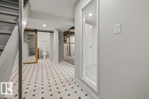 The property features a finished area with patterned floor tiles, a staircase, and a full-length mirror - 12C Castle Terrace, Edmonton, AB - Indoor Photo Showing Other Room