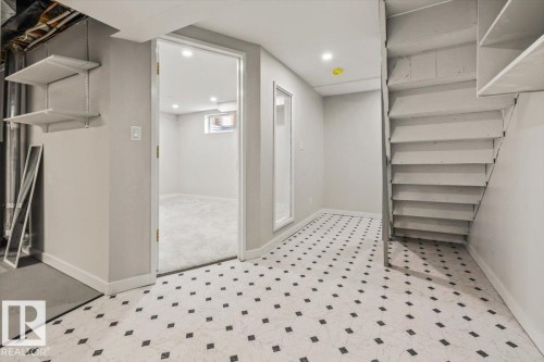 The property features a finished basement area with patterned flooring, an open doorway leading to a carpeted room, and stairs with open risers - 12C Castle Terrace, Edmonton, AB - Indoor