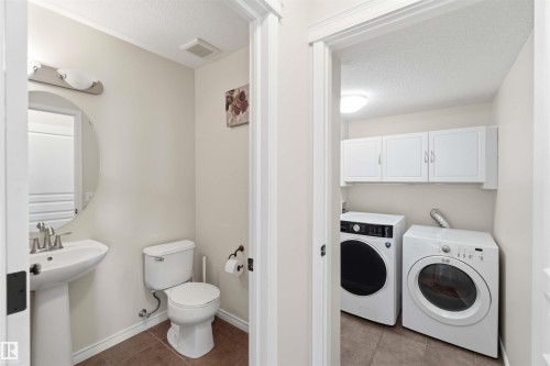 Well-maintained powder room featuring a pedestal sink, toilet, and a circular mirror - 31 Everitt Drive, St. Albert, AB - Indoor Photo Showing Laundry Room