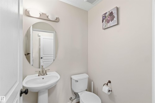 The bathroom features a pedestal sink with a modern faucet, an oval mirror, and a toilet - 31 Everitt Drive, St. Albert, AB - Indoor Photo Showing Bathroom