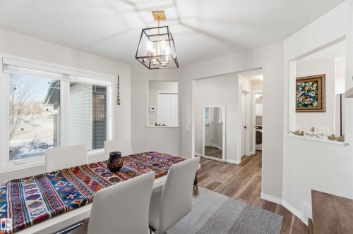 Dining area featuring a modern geometric chandelier, large window, and wood-style flooring - 31 Everitt Drive, St. Albert, AB - Indoor
