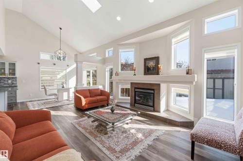 The living area features a vaulted ceiling with skylights, a fireplace with a natural stone surround, and large windows providing natural light - 31 Everitt Drive, St. Albert, AB - Indoor Photo Showing Living Room With Fireplace
