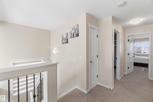 The property features neutral-toned walls, light-colored carpeting, and white trim throughout the hallway, leading to a room with a large window - 31 Everitt Drive, St. Albert, AB - Indoor Photo Showing Other Room