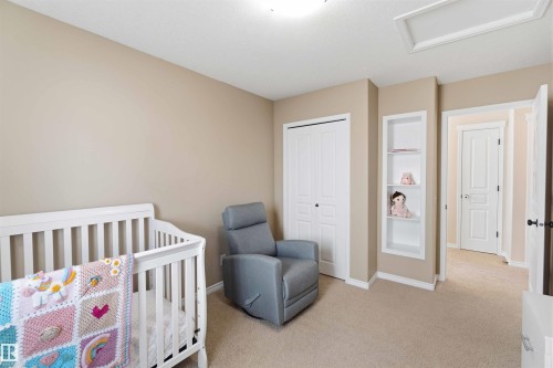 This room features neutral-toned walls, carpet flooring, a closet with bi-fold doors, and a built-in shelving unit - 31 Everitt Drive, St. Albert, AB - Indoor Photo Showing Bedroom