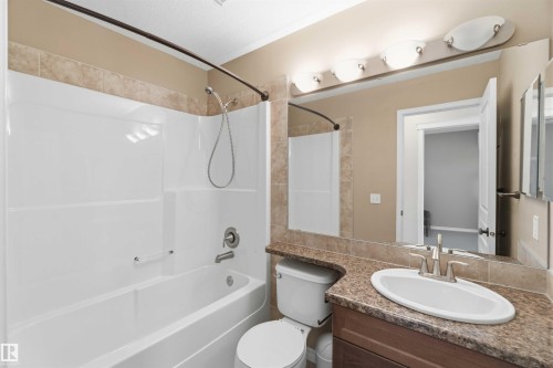 Bathroom featuring a white bathtub and shower combination with a curved shower rod, a vanity with a white sink, a chrome faucet, and a brown countertop, and a large mirror with overhead lighting - 31 Everitt Drive, St. Albert, AB - Indoor Photo Showing Bathroom