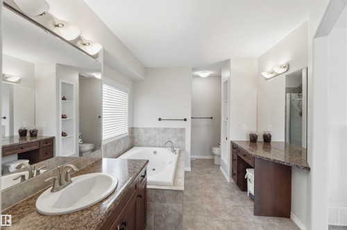 This bathroom features dual vanity areas with granite countertops and sinks, a spacious built-in tub with tile surround, and a window with blinds - 31 Everitt Drive, St. Albert, AB - Indoor Photo Showing Bathroom