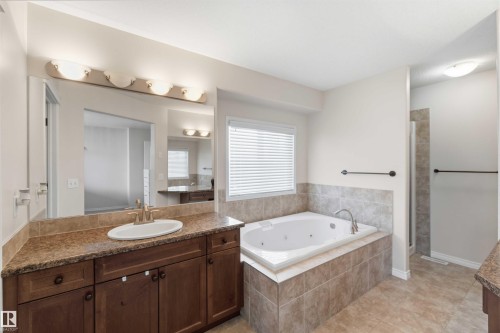 The bathroom features a spacious vanity with a built-in sink and a large mirror, a tiled soaking tub with a window above, and a separate tiled shower - 31 Everitt Drive, St. Albert, AB - Indoor Photo Showing Bathroom