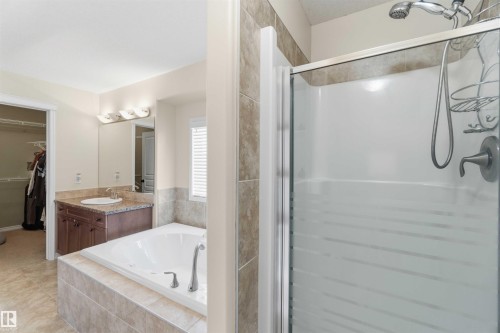 Bathroom featuring a built-in bathtub, a walk-in shower with a glass enclosure, a vanity with a mirror, and tiled flooring - 31 Everitt Drive, St. Albert, AB - Indoor Photo Showing Bathroom