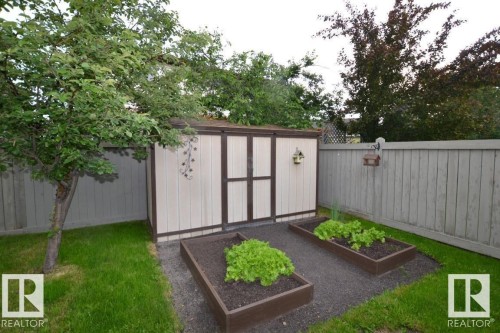 The property features a fenced yard with a shed, a mature tree, and two raised garden beds - 31 Everitt Drive, St. Albert, AB - Outdoor