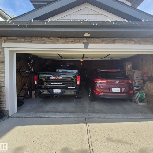 An expansive garage featuring a stone facade and a paneled overhead door, providing ample space for vehicles - 31 Everitt Drive, St. Albert, AB - 