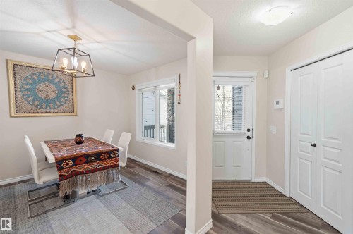 The property features a dining area with a modern chandelier and a window providing natural light, alongside an entryway with a front door and a paneled closet - 31 Everitt Drive, St. Albert, AB - Indoor Photo Showing Other Room