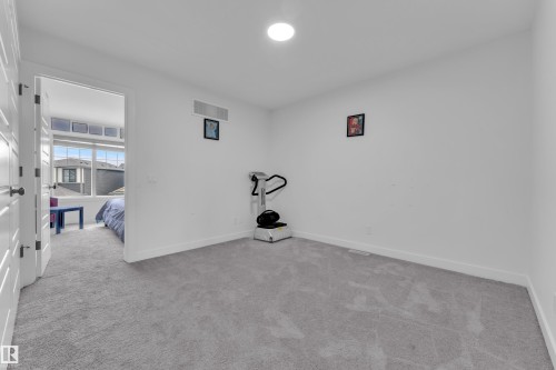 This versatile room features light gray carpeting, white walls, and a recessed ceiling light - 1645 Plum Circle, Edmonton, AB - Indoor