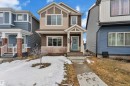 The property features a charming exterior with brown and beige siding, a light blue front door, and a covered porch - 1645 Plum Circle, Edmonton, AB  - Outdoor With Facade 