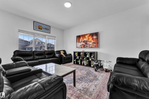 Living area featuring large windows, a ceiling light fixture, and a wall-mounted television - 1645 Plum Circle, Edmonton, AB - Indoor Photo Showing Living Room