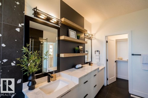 Well-appointed bathroom featuring a double vanity with stone countertops, dark cabinetry, and integrated sinks - 102 Bluff Cove, Leduc, AB - Indoor Photo Showing Bathroom