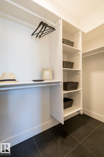 The property features a closet with built-in white shelving, a hanging rod, and a dark tile floor - 102 Bluff Cove, Leduc, AB - Indoor With Storage