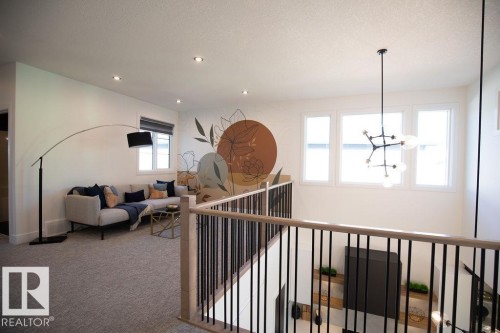 This area features a spacious layout with carpeted flooring, recessed lighting, and a decorative accent wall - 102 Bluff Cove, Leduc, AB - Indoor Photo Showing Other Room