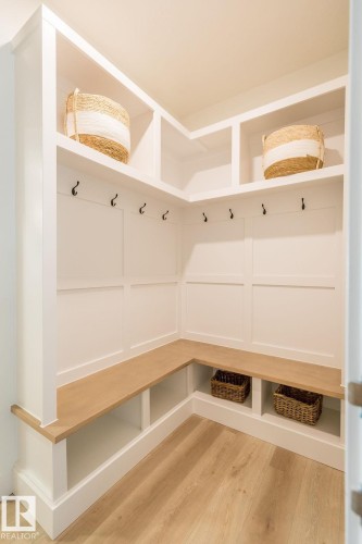 This mudroom features built-in white cabinetry with a light wood bench and light wood flooring - 102 Bluff Cove, Leduc, AB - Indoor Photo Showing Other Room