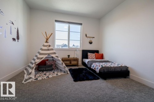 This bright room features a large window, light-colored walls, and gray carpet - 102 Bluff Cove, Leduc, AB - Indoor Photo Showing Bedroom