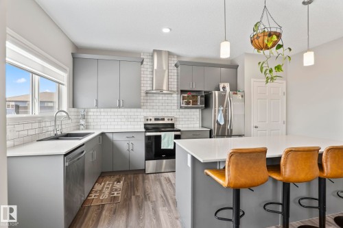 The kitchen features light grey cabinetry, white subway tile backsplash, stainless steel appliances, and a central island with a white countertop - 5164 Lark Crescent Nw, Edmonton, AB - Indoor Photo Showing Kitchen With Double Sink With Upgraded Kitchen