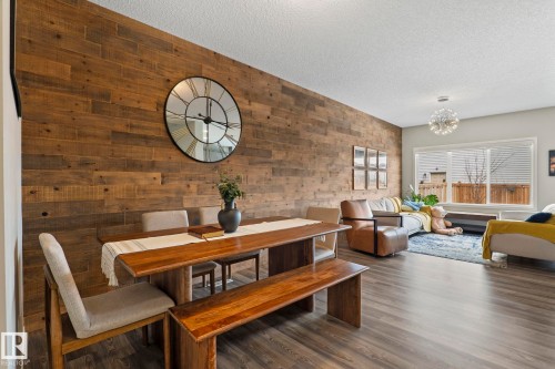 The open concept living area features a distinctive wood plank accent wall and dark wood-style flooring - 5164 Lark Crescent Nw, Edmonton, AB - Indoor Photo Showing Dining Room