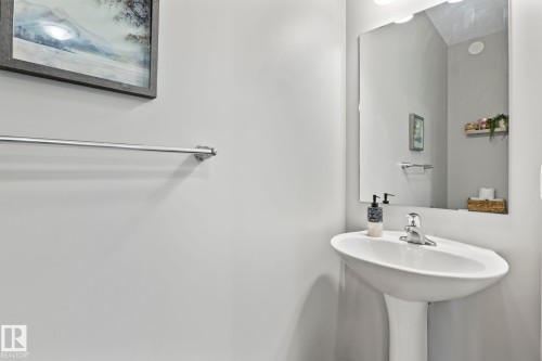 This bathroom features a pedestal sink with a chrome faucet, a wall-mounted mirror, and a chrome towel bar - 5164 Lark Crescent Nw, Edmonton, AB - Indoor Photo Showing Bathroom