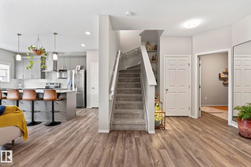 The property features a kitchen with grey cabinetry, stainless steel appliances, and a kitchen island with bar seating - 5164 Lark Crescent Nw, Edmonton, AB - Indoor Photo Showing Kitchen With Upgraded Kitchen