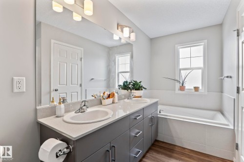Well-appointed bathroom featuring a double vanity with ample counter space and storage, a large soaking tub, and a window providing natural light - 5164 Lark Crescent Nw, Edmonton, AB - Indoor Photo Showing Bathroom