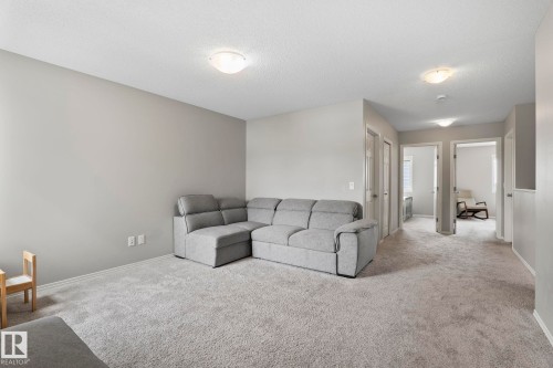 This expansive room features plush carpeting and light-colored walls, creating a bright and inviting atmosphere - 5164 Lark Crescent Nw, Edmonton, AB - Indoor