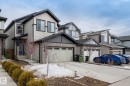 The property features light-colored horizontal siding with dark trim, a stone facade on the lower level, and an attached garage with a double door - 5164 Lark Crescent Nw, Edmonton, AB  - Outdoor With Facade 