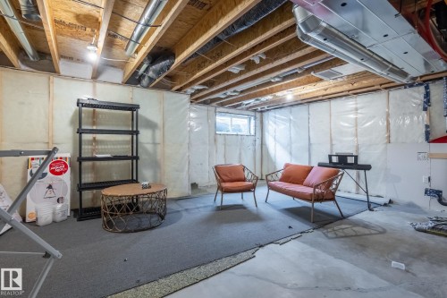 Basement space featuring exposed ceiling joists, insulated walls, and a window providing natural light - 5164 Lark Crescent Nw, Edmonton, AB - Indoor Photo Showing Basement
