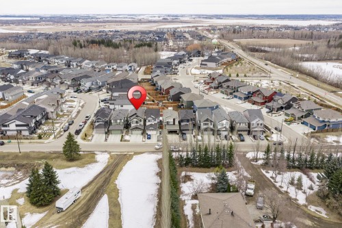Aerial view of the neighborhood showcasing houses with driveways, a paved road, and surrounding green spaces with trees - 5164 Lark Crescent Nw, Edmonton, AB - Outdoor With View