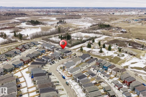 Aerial view displaying the property within a residential development, surrounded by open land and distant structures - 5164 Lark Crescent Nw, Edmonton, AB - Outdoor With View