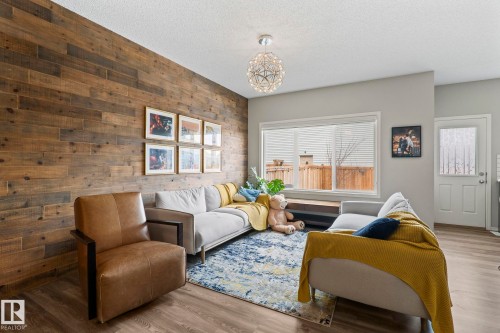 This inviting living space features a striking accent wall with horizontal wood paneling, complemented by light gray painted walls - 5164 Lark Crescent Nw, Edmonton, AB - Indoor Photo Showing Living Room