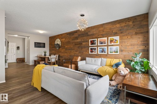 The living area features a striking wood accent wall and durable wood-style flooring - 5164 Lark Crescent Nw, Edmonton, AB - Indoor Photo Showing Living Room
