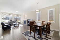 This open concept living space features hardwood floors, a natural stone fireplace, and large windows providing natural light - 