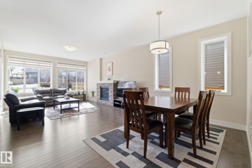 This open concept living space features hardwood floors, a natural stone fireplace, and large windows providing natural light - 3235 Abbott Crescent, Edmonton, AB - Indoor