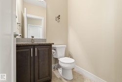 This powder room features a dark wood vanity with a granite countertop, a neutral-toned toilet, and light-colored walls - 