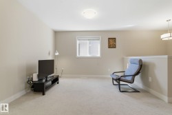 Living area featuring light-colored carpet, a window with blinds, and neutral-toned walls - 