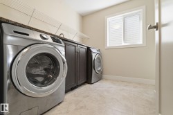 Laundry area featuring tile flooring, a window with blinds, dark wood cabinetry with a granite-style countertop, and wire shelving - 