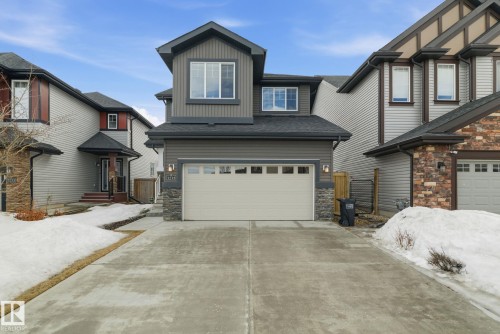 The property features a concrete driveway and an attached garage with a light-colored door - 3235 Abbott Crescent, Edmonton, AB - Outdoor With Facade