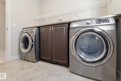 Dedicated laundry area featuring tile flooring, dark wood cabinetry, a sink, and a countertop - 