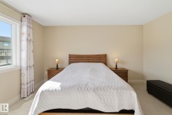 The bedroom features a window with decorative curtains, providing natural light, and soft carpeting - 