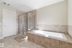 This bathroom features a tiled floor, a tiled shower enclosure with a glass door, and a built-in bathtub with tiled surround - 