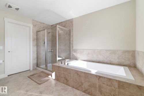 This bathroom features a tiled floor, a tiled shower enclosure with a glass door, and a built-in bathtub with tiled surround - 3235 Abbott Crescent, Edmonton, AB - Indoor Photo Showing Bathroom