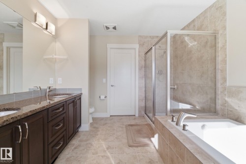 Bathroom featuring a double vanity with granite countertops, a tiled shower with a glass enclosure, a white built-in bathtub, and tiled flooring - 3235 Abbott Crescent, Edmonton, AB - Indoor Photo Showing Bathroom