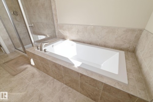 Bathroom with a built-in bathtub, a walk-in shower with a glass enclosure, and tiled walls and floors - 3235 Abbott Crescent, Edmonton, AB - Indoor Photo Showing Bathroom