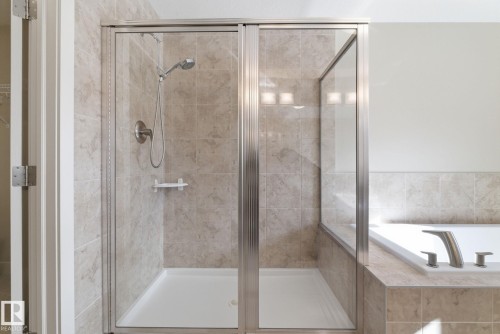 The bathroom features a tiled shower with a glass enclosure and a white bathtub with brushed nickel fixtures - 3235 Abbott Crescent, Edmonton, AB - Indoor Photo Showing Bathroom